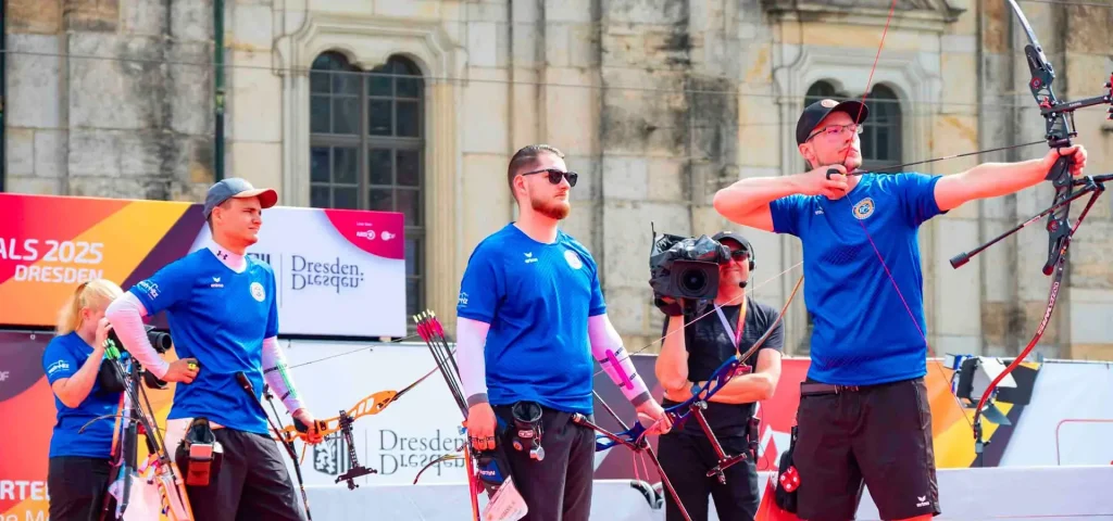 drei Männer in blauen Shirts mit Bögen und Pfeilen